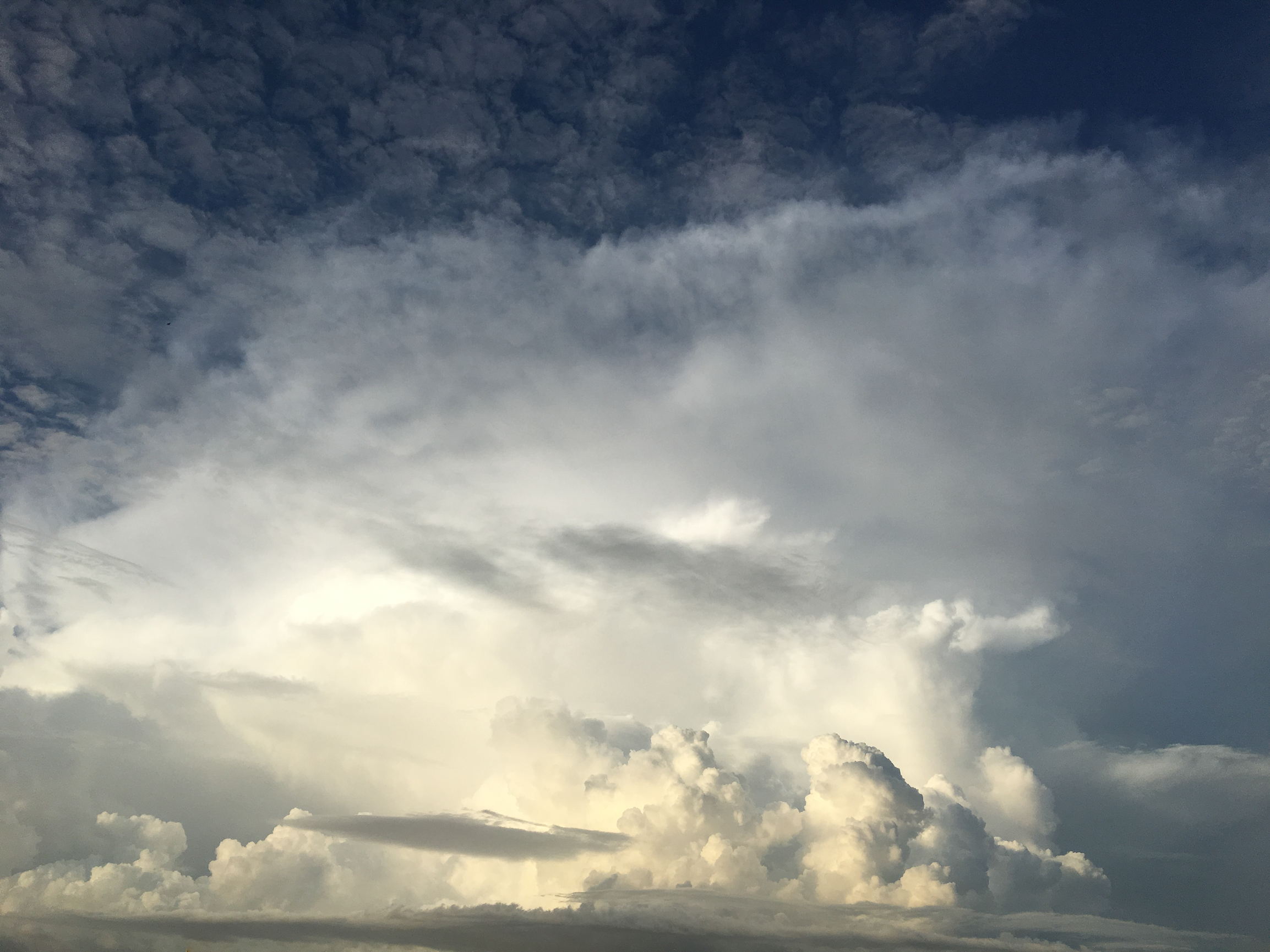 Dramatic white and cream clouds rise in a dark blue sky, inspiring expansion and soulful feelings.